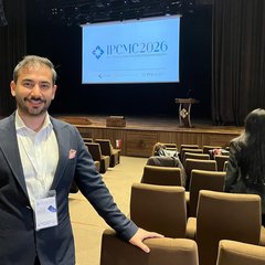 Kutbeddin Ağca in the conference hall at Hasan Kalyoncu University, with IPCMC 2026 on the screen above the stage behind him