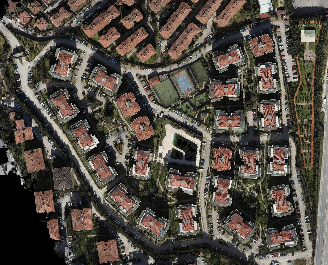 Sitenin drone ortofotosu: kiremit çatılı bloklar, havuz, spor sahaları, yollar ve otoparklarıyla konut sitesi